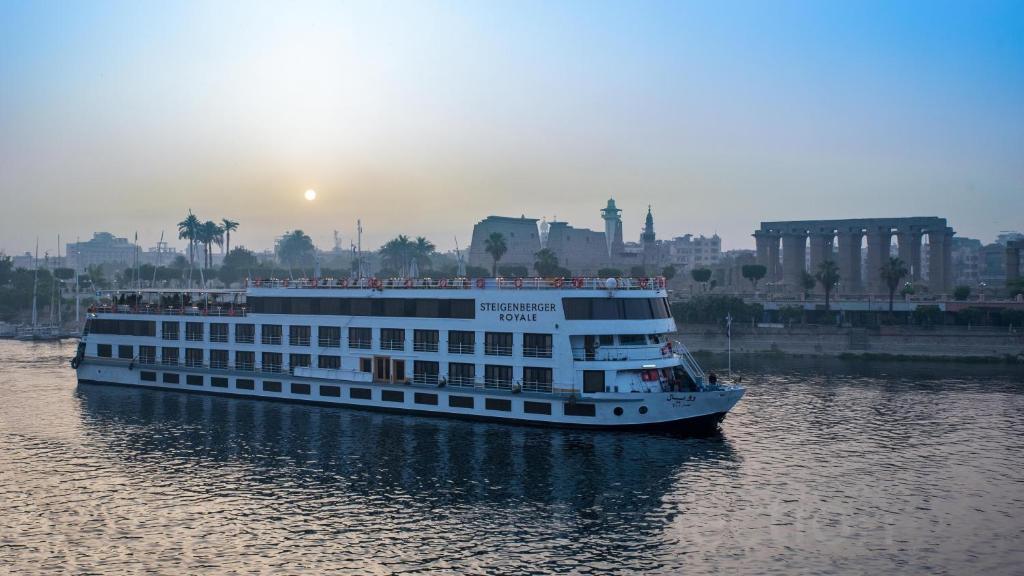 a cruise ship on the water with a city in the background at Steigenberger Royale Nile Cruise - Every Thursday from Luxor for 07 & 04 Nights - Every Monday From Aswan for 03 Nights in Aswan