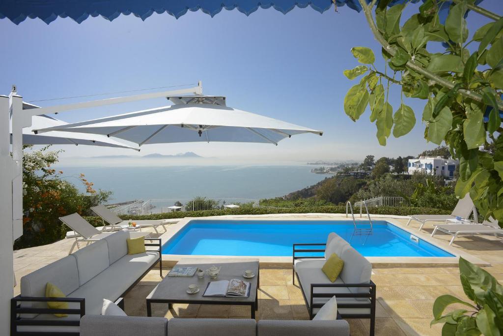 a villa with a swimming pool and a table and an umbrella at La Demeure in Sidi Bou Saïd