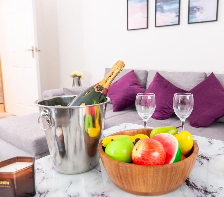 a bowl of fruit on a table with two wine glasses at 3-Bed Apartment Central London - 15 Mins walk to Kings Cross by Seren Short Stays in London