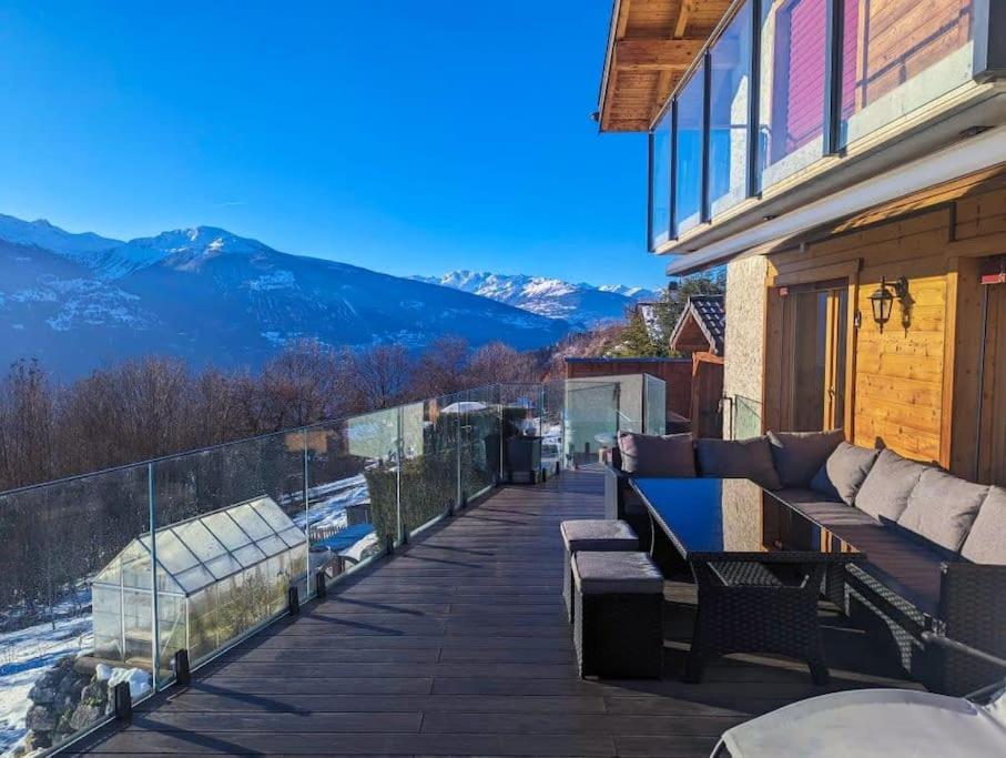 a porch with a couch and a view of the mountains at Luxury Chalet: Alpine Magic with Terrace Views in Crans-Montana