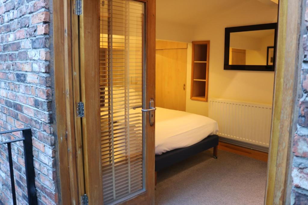 um pequeno quarto com uma cama e uma parede de tijolos em Lower Turks Head em Manchester