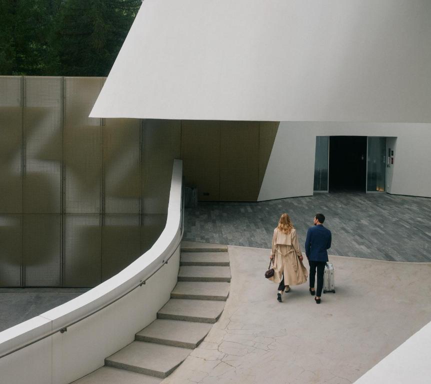 Ein Mann und eine Frau gehen eine Treppe hinauf in einem Gebäude in der Unterkunft 7132 Hotel in Vals