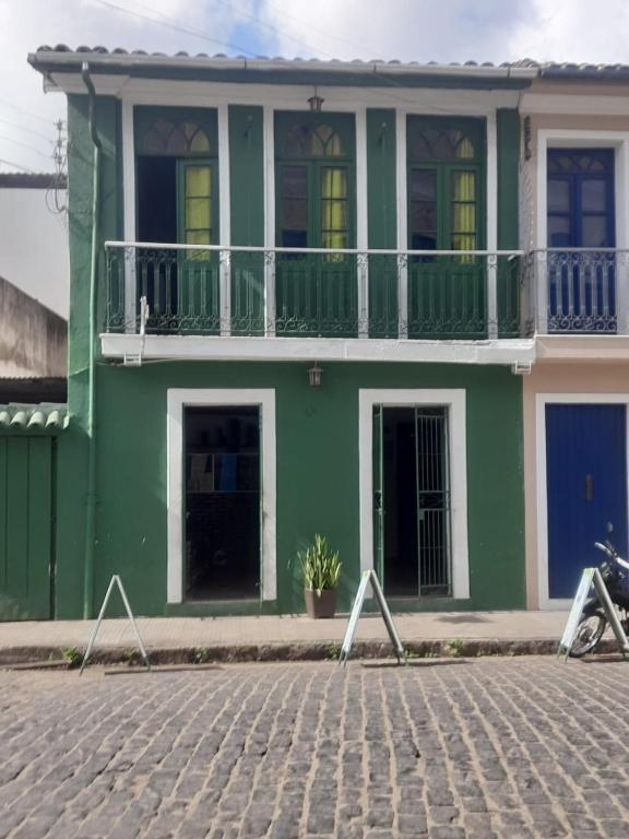 een groen huis met een balkon in een straat bij Pousada do Guerreiro in Cachoeira