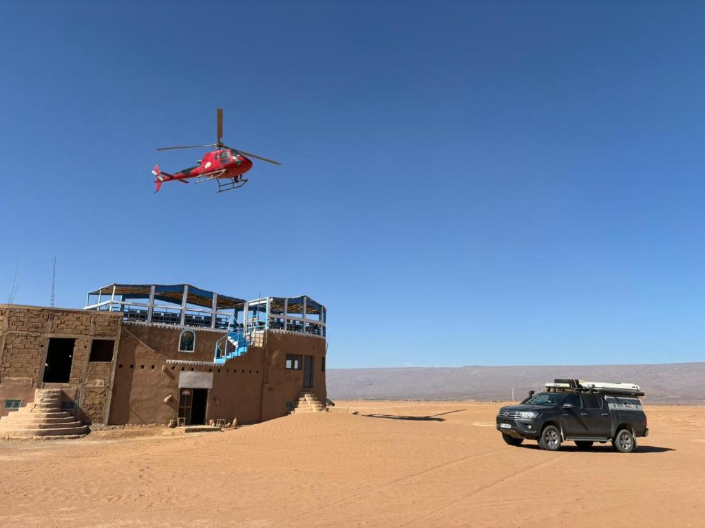 un helicóptero sobrevolando un edificio en el desierto en désert tours & Hôtel Titanic lac irik, en Foum Zguid