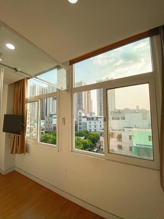 a room with two windows with a view of a city at Aloha House Apartment in Ho Chi Minh City