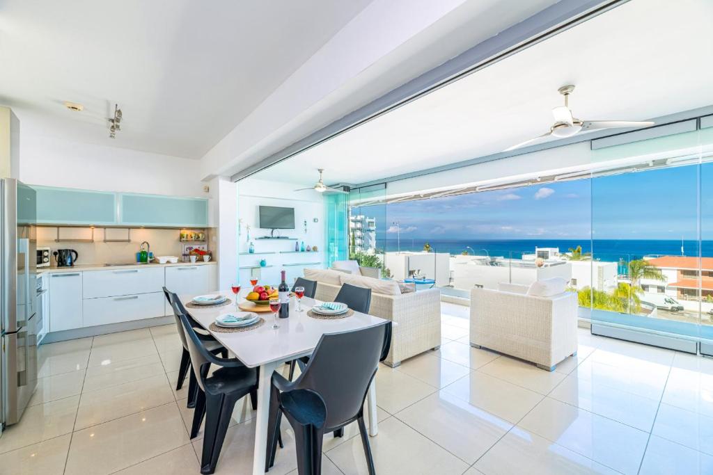 una cucina e un soggiorno con tavolo e sedie di Silver Sands Penthouse a Protaras