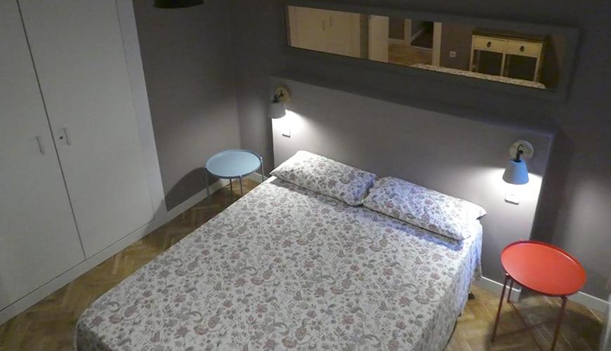 a bedroom with a bed with two chairs and a mirror at Casa Mele 1 in Lleida