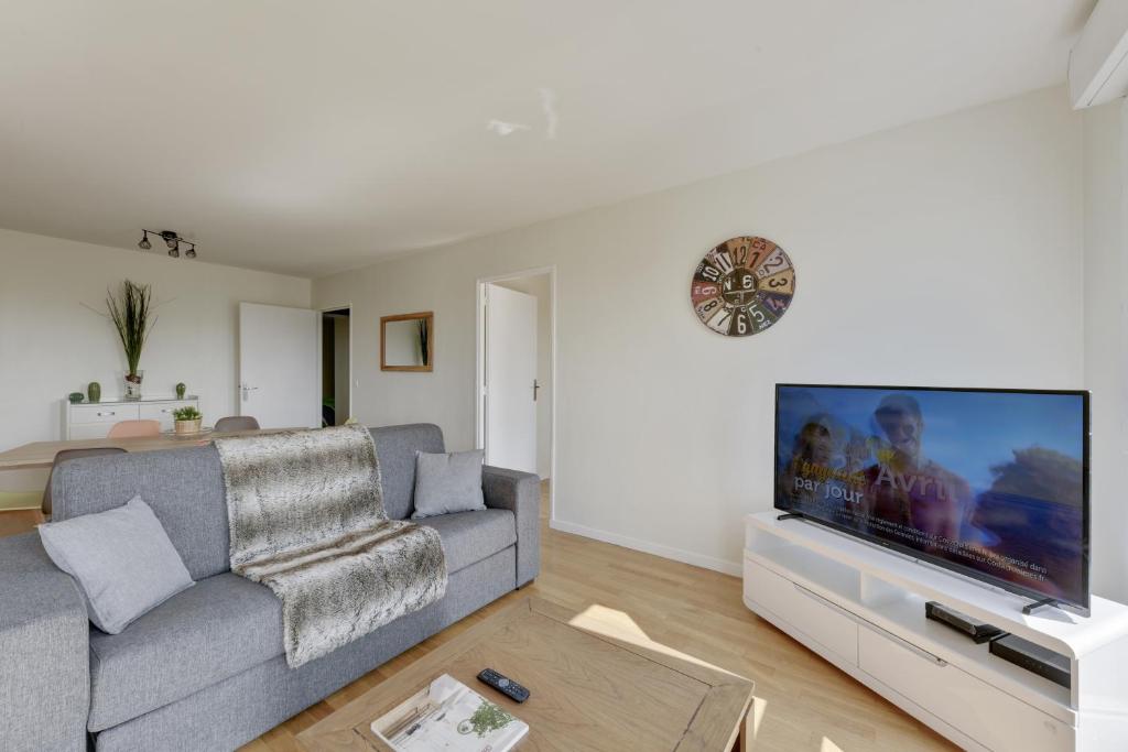 a living room with a couch and a flat screen tv at Chic apartment with superb view of the eiffel tower in Saint-Denis