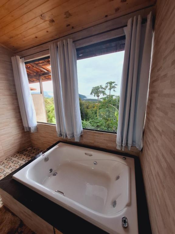a bath tub in a room with a window at Luar de Minas suites in Lavras Novas