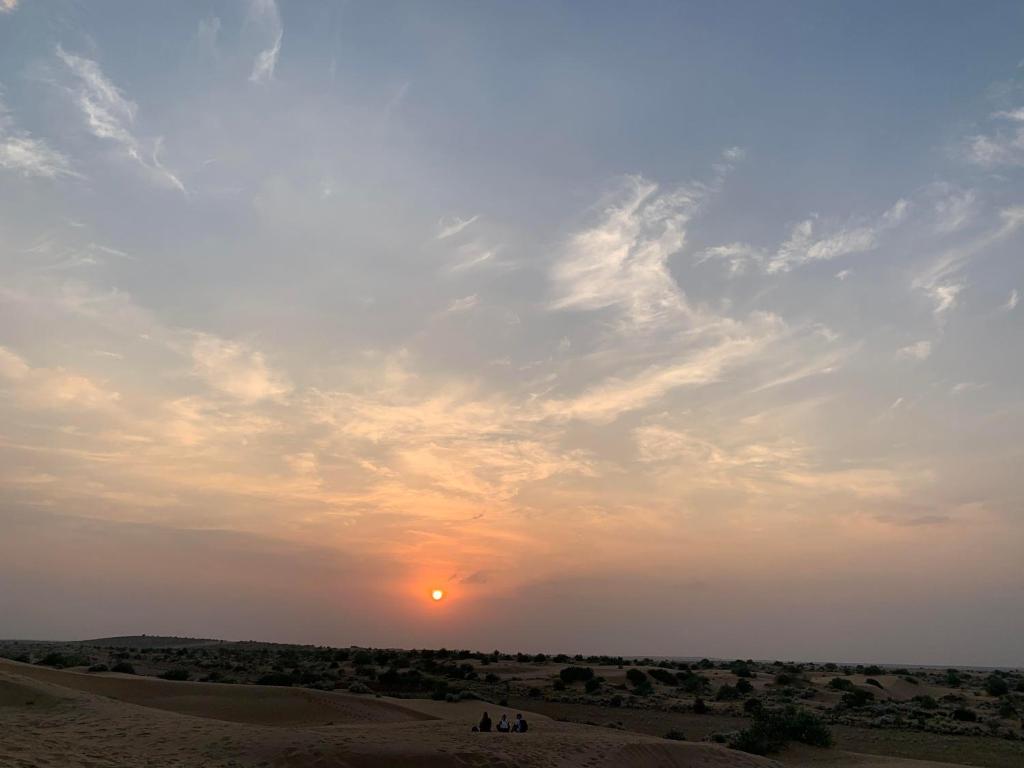 un coucher de soleil dans le désert avec le soleil dans le ciel dans l'établissement hostel Wyra home stay Jaisalmer, à Jaisalmer