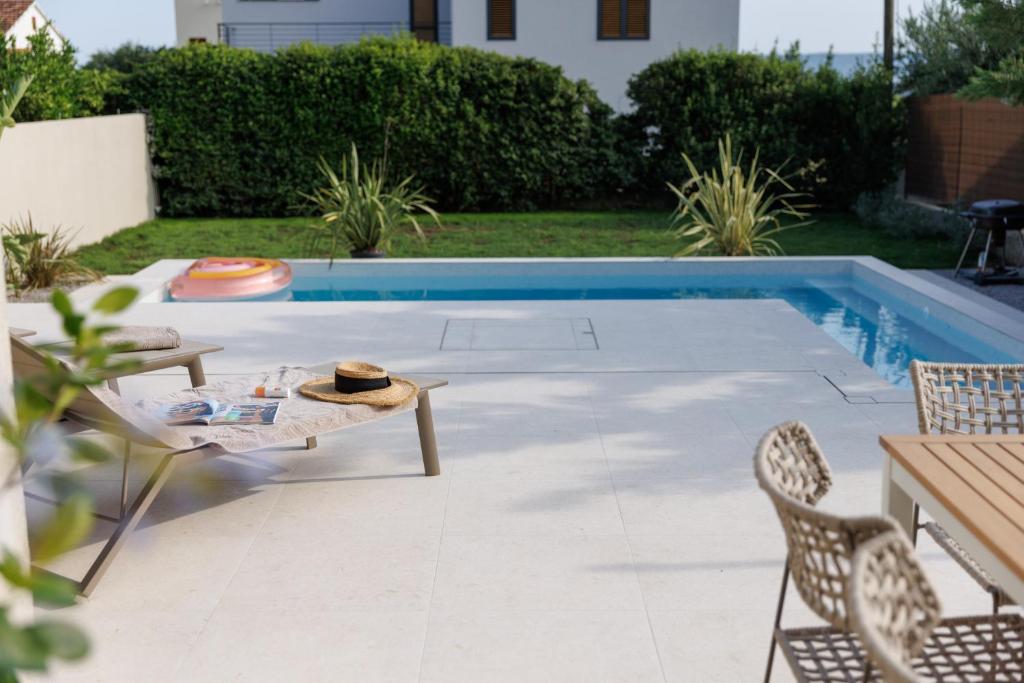 un patio con tavolo e sedie accanto alla piscina di Villa Botanica - New family house near the sea a Kaštela (Castelli)