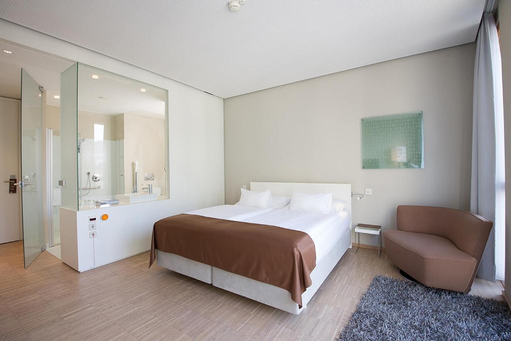 a bedroom with a large bed and a chair at Hotel Am Domplatz - Adult Only in Linz