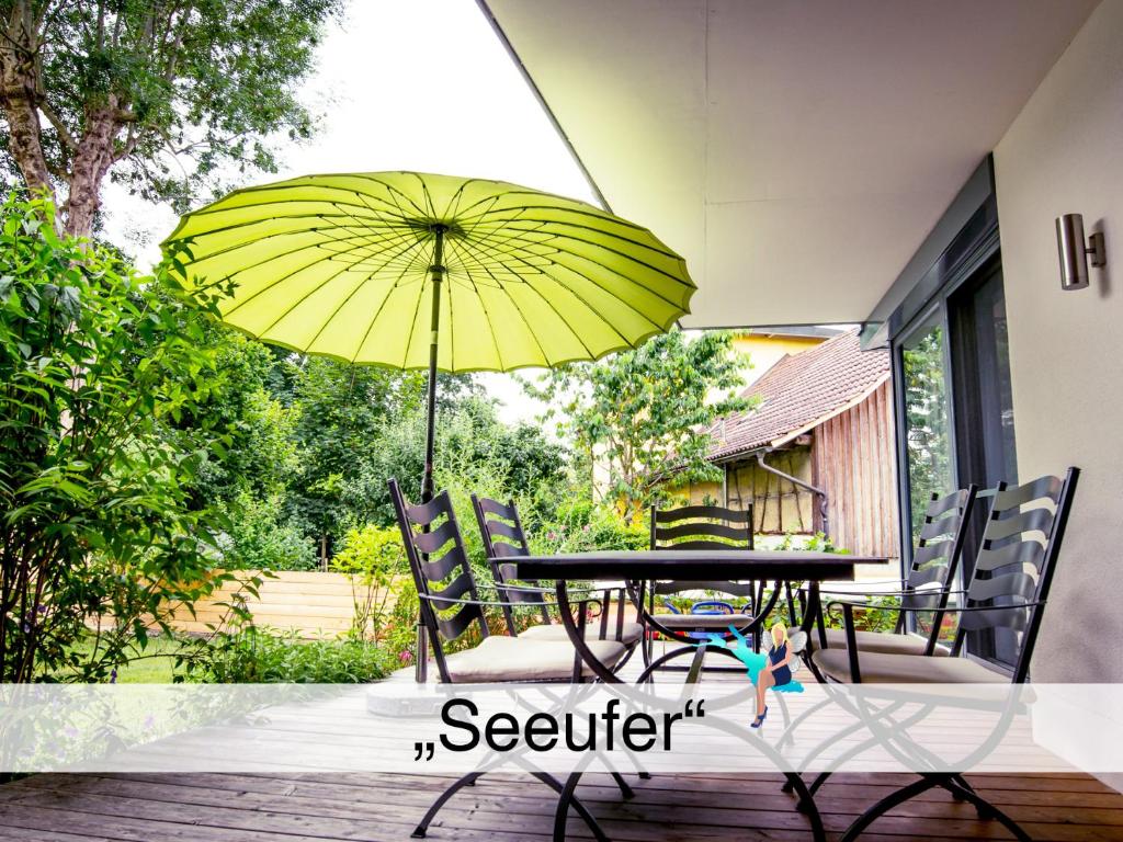 einen Tisch und Stühle mit gelbem Regenschirm auf einer Terrasse in der Unterkunft Ferienwohnung Seeufer in Kressbronn am Bodensee