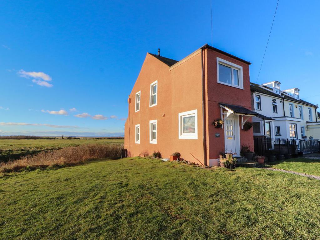 een huis aan de zijkant van een grasveld bij Woodbine Cottage in Maryport