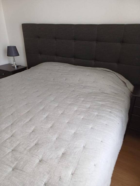 duże białe łóżko z czarnym zagłówkiem w sypialni w obiekcie Depto 1 ambiente central w mieście Antofagasta