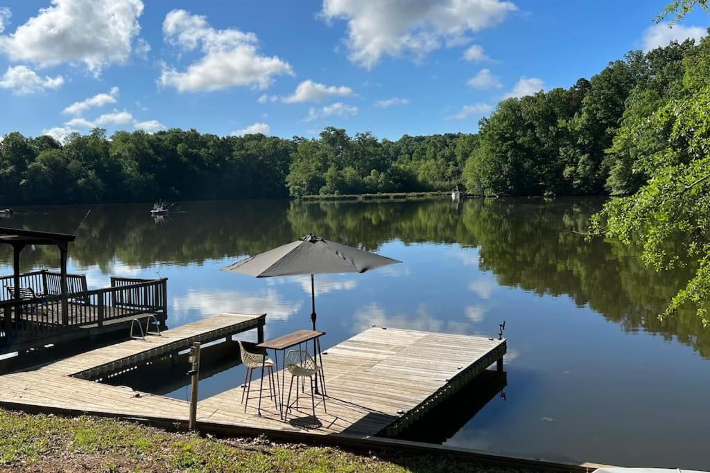 ein Steg mit Sonnenschirm und Stühlen an einem See in der Unterkunft Charming Romantic Lakefront Cottage or Guest Room Depending on Availability Near Golf in Anderson