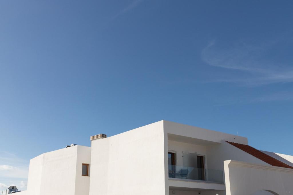 Un edificio blanco con un cielo azul al fondo. en Blank - Alojamento Local, en Santo Estêvão