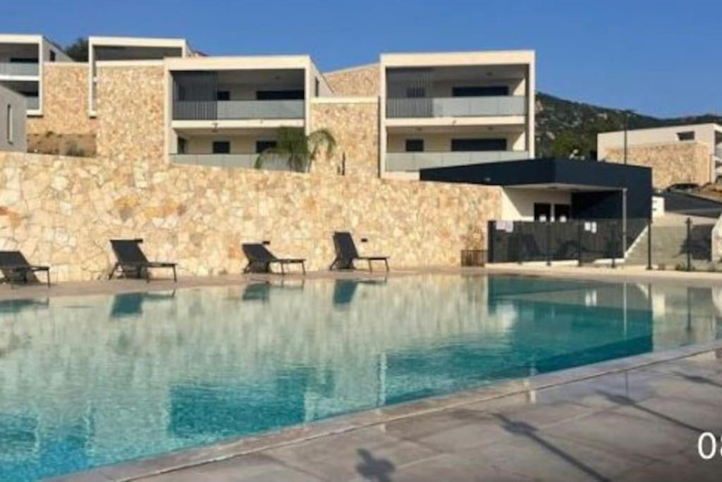 - une piscine avec des chaises en face d'un bâtiment dans l'établissement Appartement de type T3 - Résidence avec piscine, à Calvi