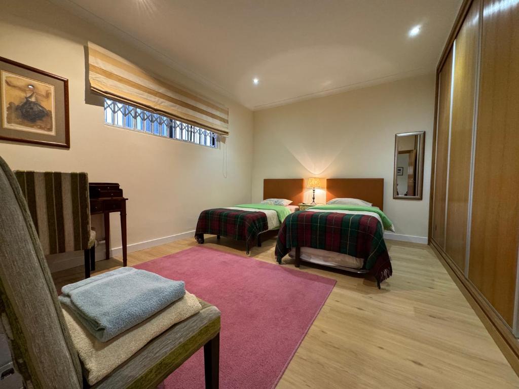 a bedroom with two beds and a chair and a window at Quinta da Vitoria in Sacavém