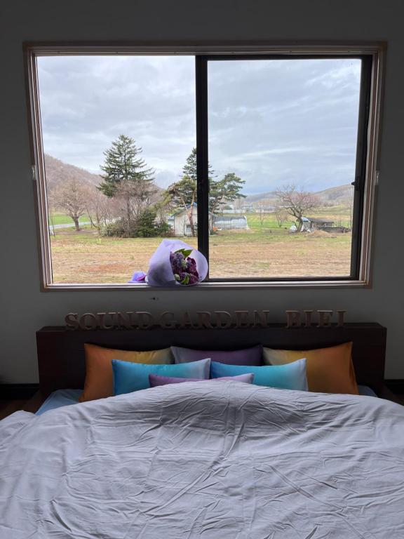 a bedroom window with a teddy bear sitting on a bed at Sound Garden Biei, Cricket in Biei