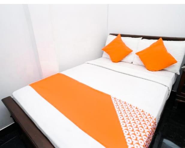 a bed with orange and white sheets and pillows at River Edge Safari House in Udawalawe