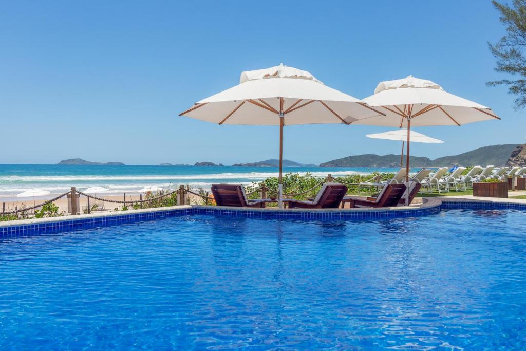 布希奧斯的住宿－雷萊波利酒店，一个带椅子和遮阳伞的游泳池和海滩