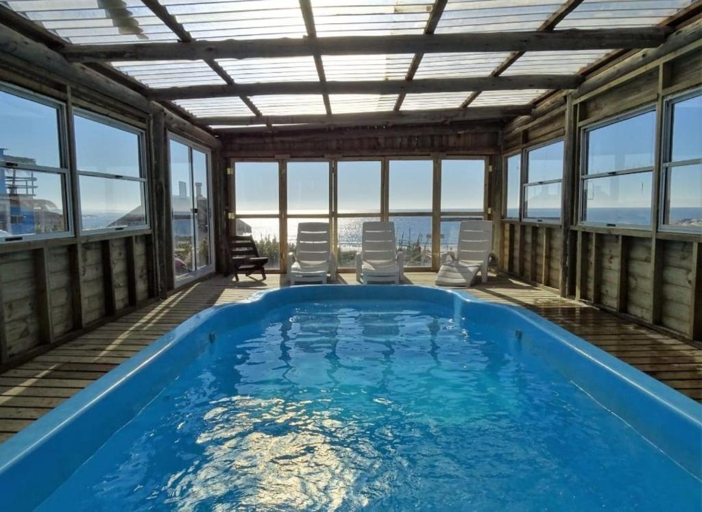 een groot zwembad in een huis met ramen bij Frente playa in Punta Del Diablo