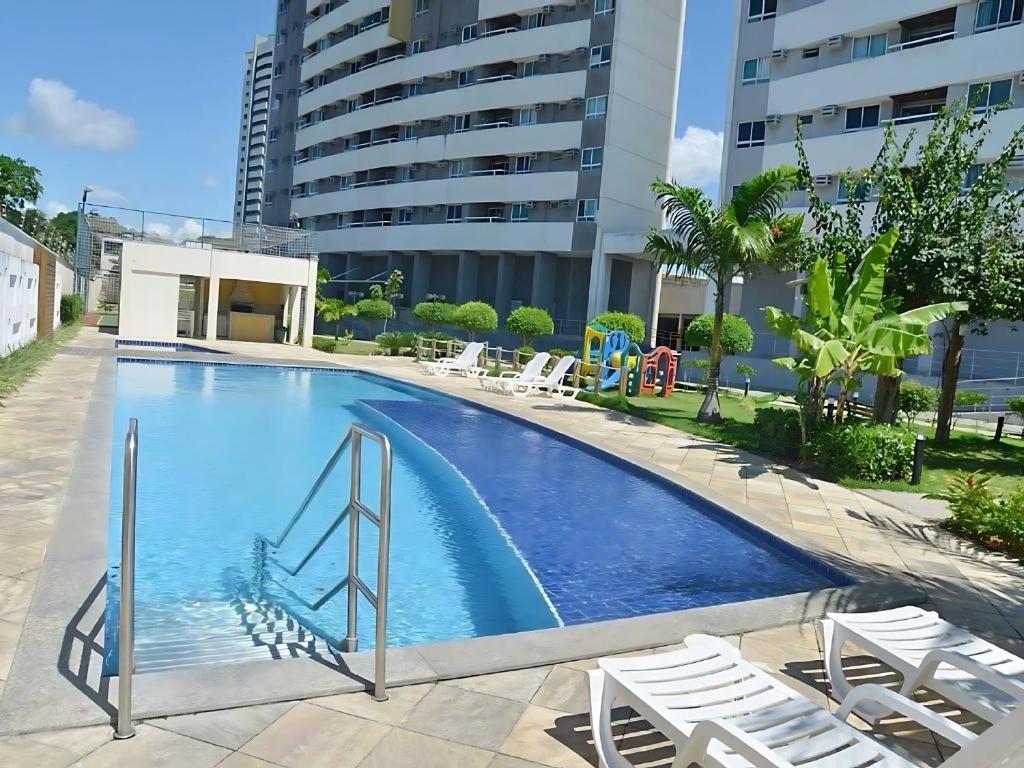 a large swimming pool with chairs and a building at Natal Verano Ponta Negra in Natal