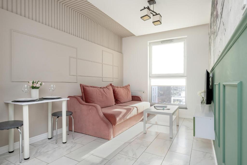 a living room with a pink couch and a table at Motława River Old City Gdańsk Apartment by Renters in Gdańsk