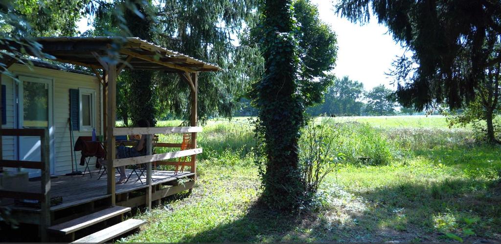 une cabane avec terrasse couverte à côté d'un arbre dans l'établissement Camping le Rural, à Tibiran-Jaunac
