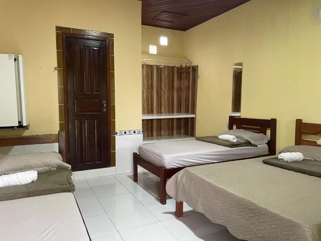 a hotel room with two beds and a tv at Pousada Cuiarana Salinas in Salinópolis