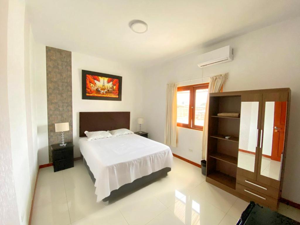 1 dormitorio con cama blanca y ventana en D'eluxe Hotel Talara ubicado a 5 minutos del aeropuerto y a 8 minutos del Centro Civico en Talara