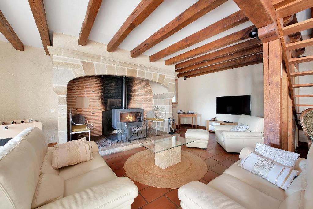 a living room with a fireplace and white furniture at Domaine du Segala in Bagnac