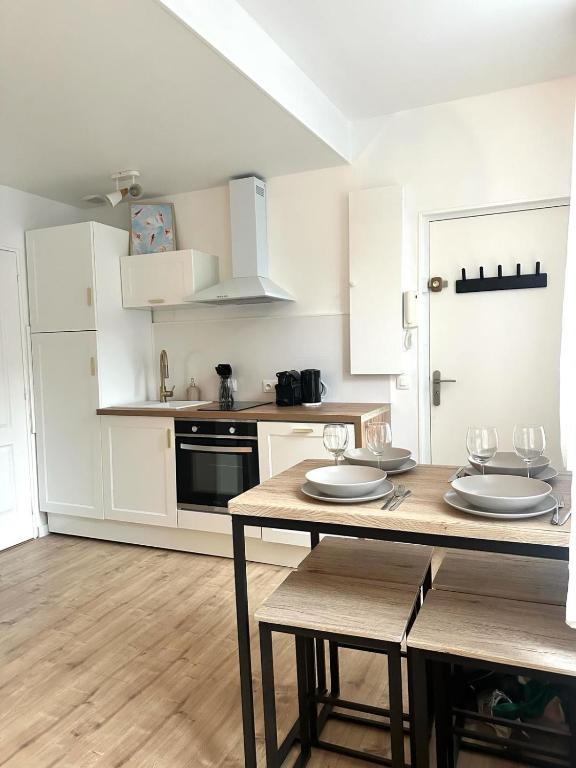 una cocina con armarios blancos y una mesa con sillas. en Appartement T2 hyper centre, en Dieppe