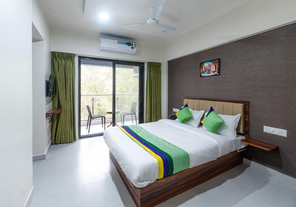 a bedroom with a large bed and a balcony at Treebo Trend Raana Encore - Near Magarpatta in Pune