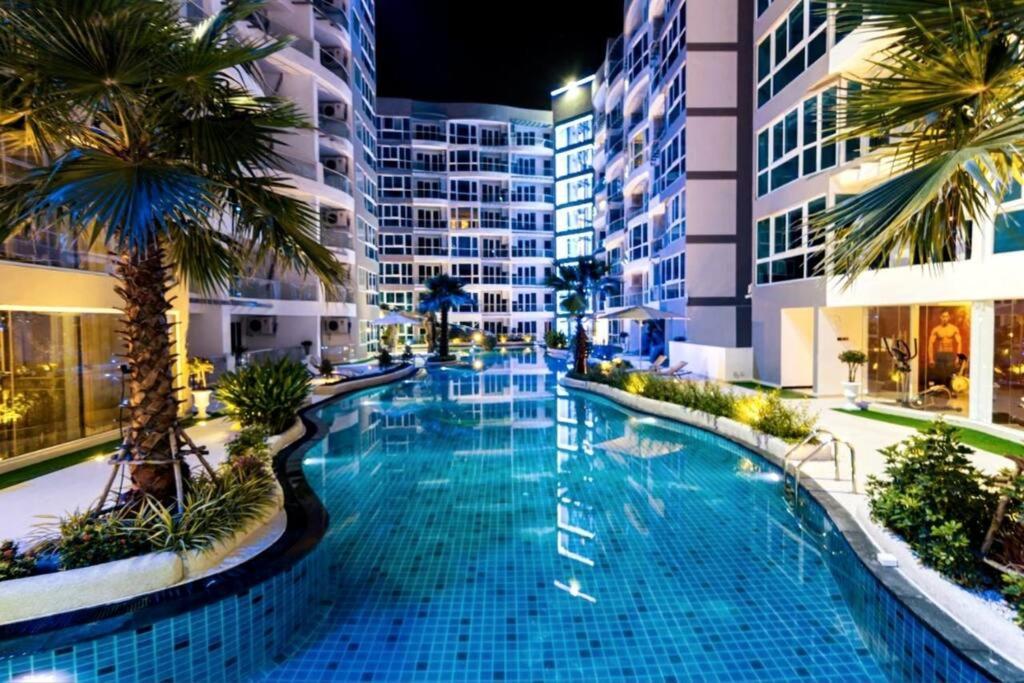 芭達雅中心的住宿－Grand Avenue, Luxury Suite, 72sqm pool view with lounge area，棕榈树建筑中间的游泳池