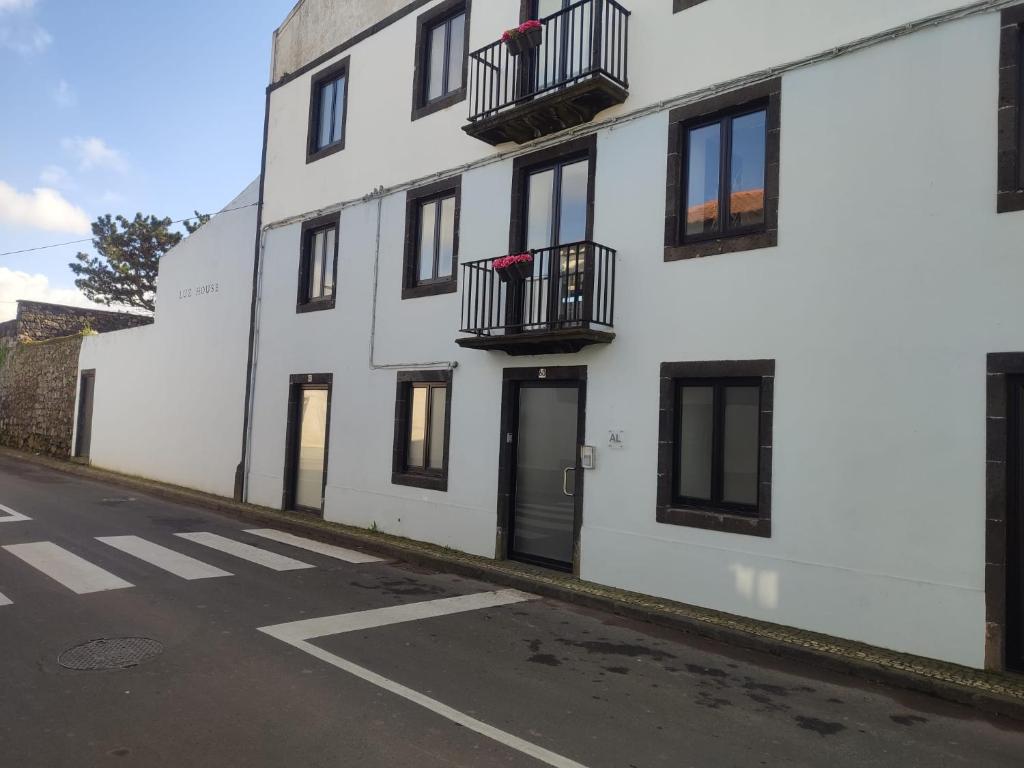 un edificio blanco con ventanas negras y balcones en una calle en Fenais da Luz House, en Fenais da Luz