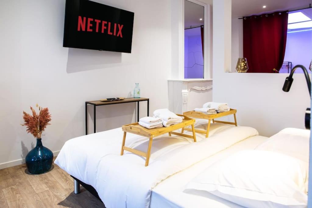 um quarto com duas camas com uma mesa em NG SuiteHome - Lille l Tourcoing Winoc - Balnéo - Sauna - Netflix - Wifi em Tourcoing