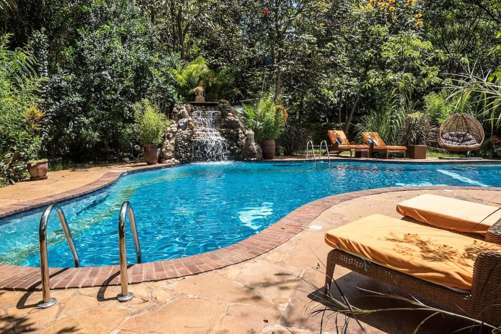 a swimming pool with a waterfall in a yard at The Jungle Oasis with heated pool in Nairobi