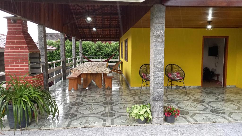 a yellow house with a table and chairs on a patio at Casa boa vista in Campos do Jordão