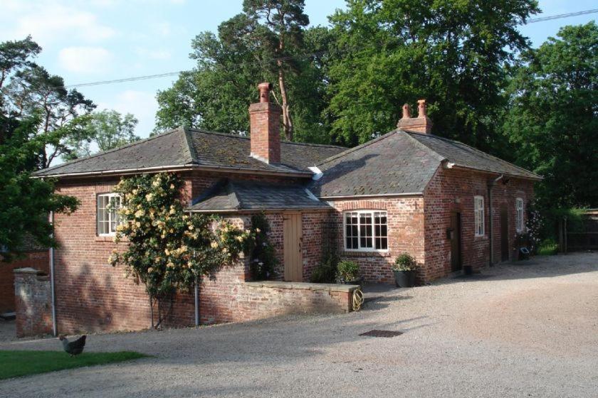 an old brick house with a tree in front of it at The Coach House at Bryngwyn Hall in Llanfyllin