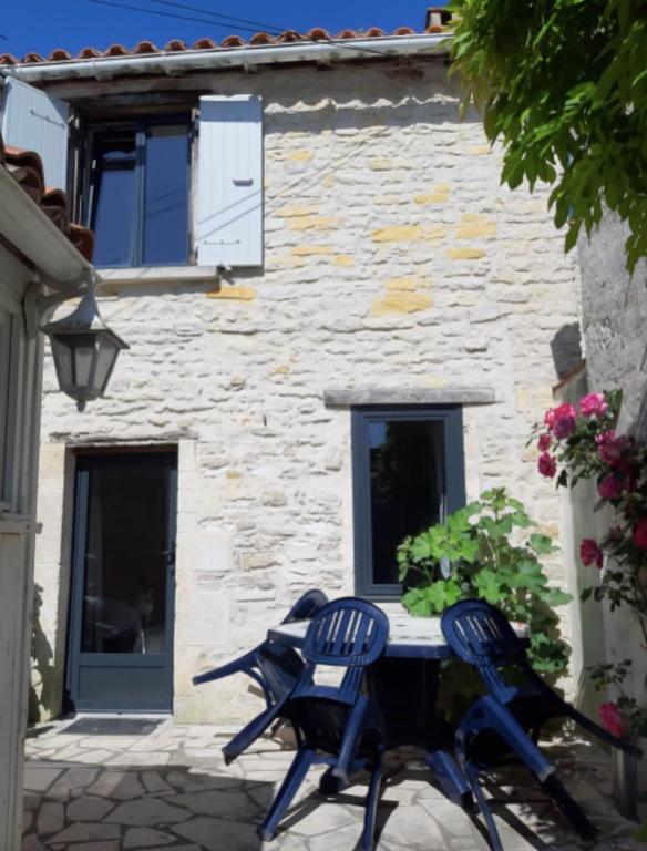 une table et des chaises devant un bâtiment en pierre dans l'établissement Lovely cosy house, à La Flotte