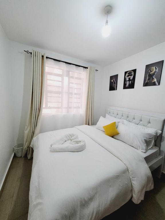- une chambre avec un grand lit blanc et une fenêtre dans l'établissement Queen homes, à Ruiru
