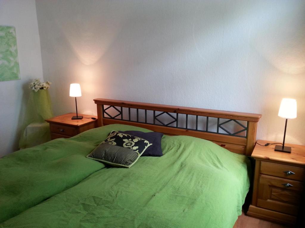 a bedroom with a green bed with two lamps at Ferienwohnung am Nürburgring in Adenau