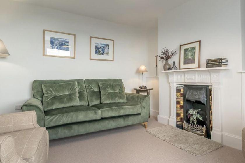 a living room with a green couch and a fireplace at Ty-Newydd, Frongaled in Dyffryn