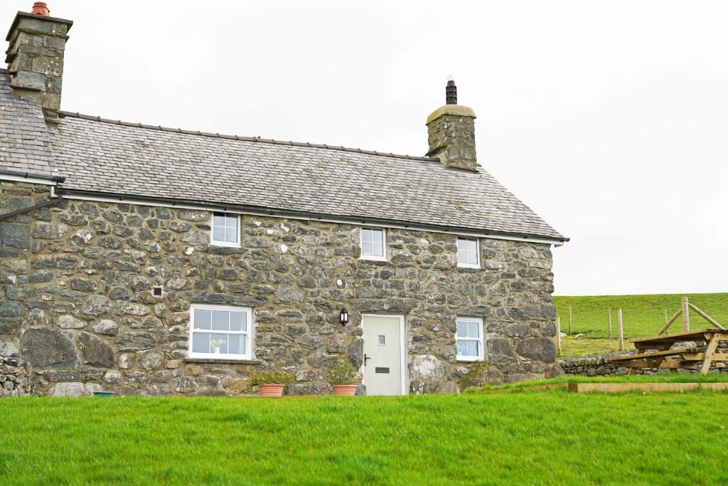 an old stone house with a white door at Hen-Dy, Frongaled in Dyffryn