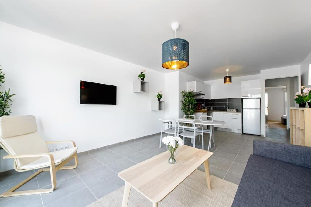 Una sala de estar con un jarrón de flores sobre una mesa. en Magnifique appartement à proximité de Paris, en Saint-Ouen