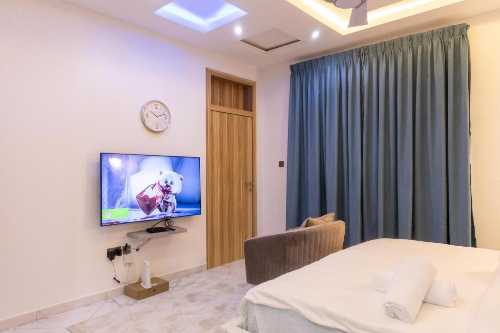 Un dormitorio con una cama y un televisor en una pared. en Premier Studio Apartment, East Airport, en Accra