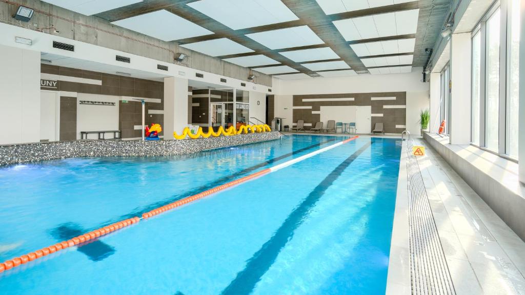 a large indoor swimming pool with blue water at AQUAMARINA Onyx, Sun & Snow in Międzyzdroje