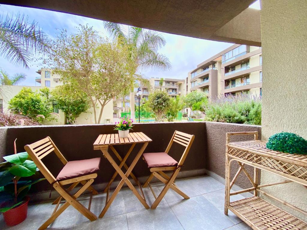 un patio con 2 sillas y una mesa en el balcón en Apartamentos Alma Surire, en Arica